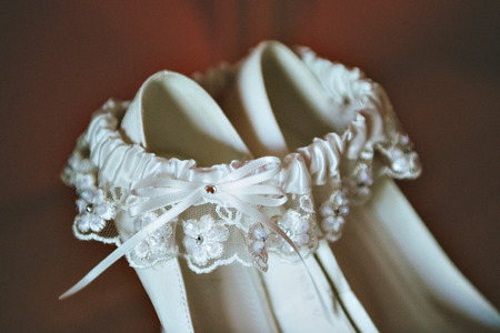 White wedding shoes with decoration on the foot, on wooden tableの写真素材