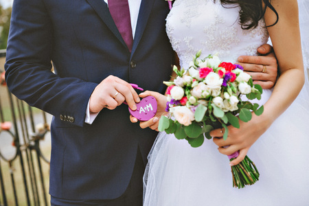 The decorative lock in hands of newlyweds, Space for text on lock. Wedding Bouquet on background.の写真素材