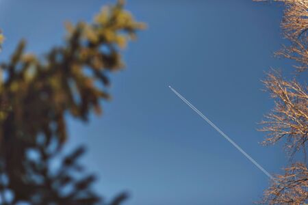 Fighter aircraft fuel trace in the turkish blue cloudy sky over trees.の写真素材