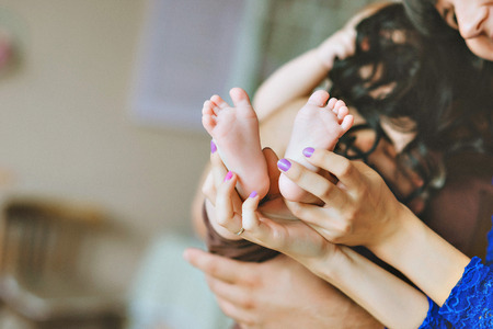 small twin legs in mom's hands with gentle toning. the child has tangled hair momの写真素材
