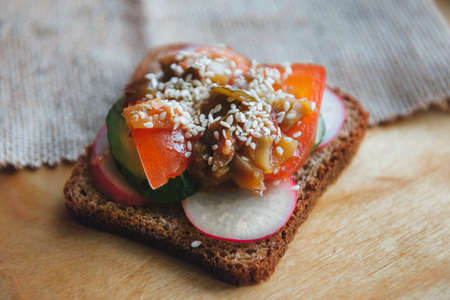 Vegetarian sandwich with radish, tomato, herbs and vegetables on wooden backgroundの写真素材