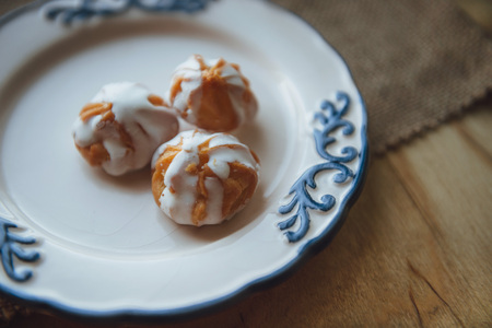 Home made choux cream on white plate. Over on wood table. Top view. with a white glazeの写真素材