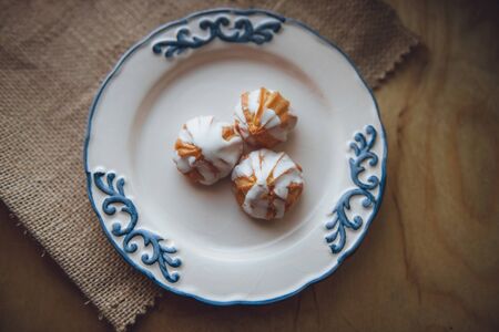 Home made choux cream on white plate. with a white glaze. on wooden background. Over on wood table....