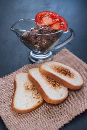Pate vegetarian beans with tomato. Veg sandwich. Snack on slate. The toasted bread. White bread with sesame seeds on a black background. Snacks on wooden backgroundの写真素材