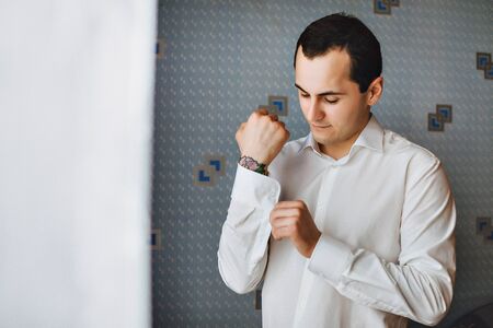 Man buttons cuff links. The bridegroom going to the wedding. Wedding morning. Men's hand tattoos