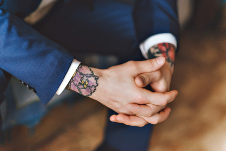 A man's hand in the tattoo. The man in the suit. Blue jacket. Hands close up of young tattooed man portrait. Hipster styleの写真素材