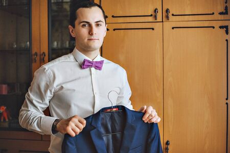 The man holding the jacket. The groom in shirt, jacket and serenity bow tie. Blue jacket. Hands tattooedの写真素材