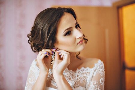 Woman putting on diamond earrings. Caucasian beauty lady trying and shopping jewelryの写真素材