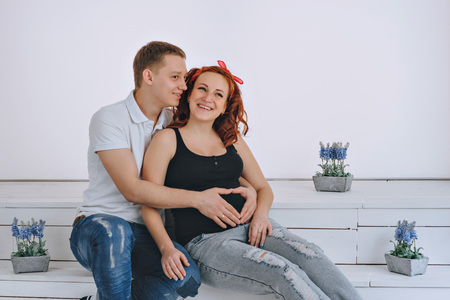 Pregnancy. The belly of a pregnant girl and her husband. The husband keeps his hand on the belly wife. Future parents. Man and woman looking at pregnant belly and laughの写真素材