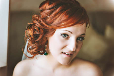 portrait of red-haired young woman bride, smiling, looking at the camera.