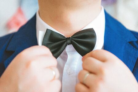 butterfly of violet color on a neck at the man. Man wears purple, purple bow-tie. The bridegroom...
