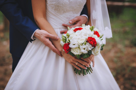 Bridal bouquet red white flowers in hands of the newlyweds.の写真素材