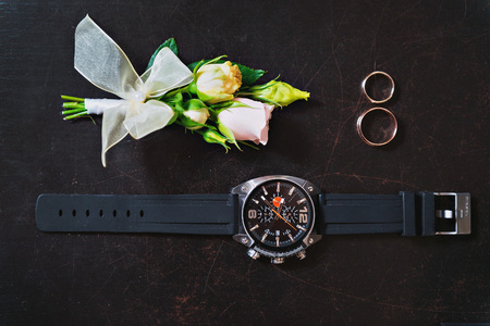 watches, wedding rings and buttonhole on a dark background.