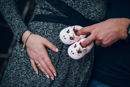 Man embracing pregnant naked belly of his wife. Pink booties.