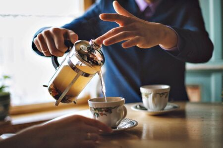 Man pouring herbal tea in a mug of French press.の写真素材