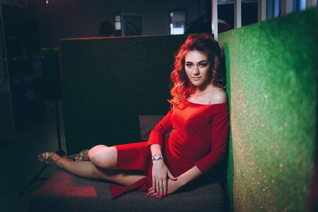 Young beautiful woman in red dress, reclining on a green backgroundの写真素材