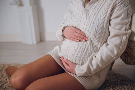 The woman hugs your pregnant belly. Romance
