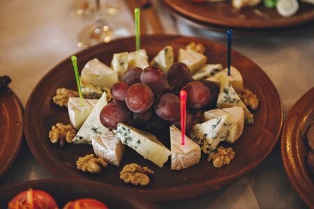 different types of cheese with red grapes on a ceramic plate on the table, top view. Dor blue.の写真素材