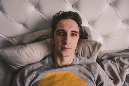 A man in a grey track suit in bed. Close-up portraitの写真素材