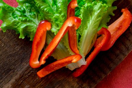 Salad of fresh vegetables. Red pepper and green salad on dark wooden background. Vegetarian foodの写真素材