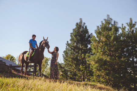 Romantic young couple in love, walk on horseback, on nature background. A woman touches the hand of a horse. Concept: love, romance, Hobbies.の写真素材