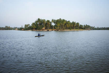A villager is rowing boat to island with coconut trees の写真素材