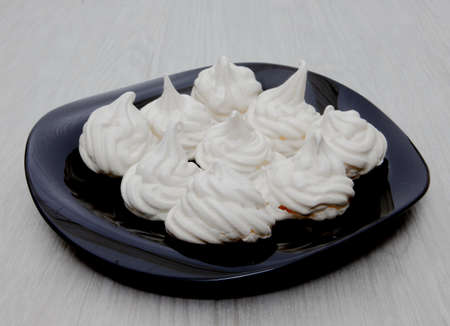 meringues on black plate and white backgroundの写真素材