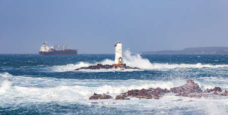 The lighthouse of the Mangiabarche shrouded by the waves of a mistral wind stormの写真素材
