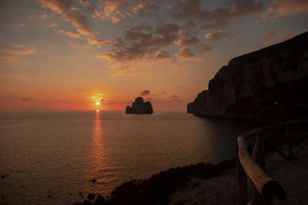 the sunsets behind the faraglione of the sugar loaf, a limestone formation in southern Sardinia