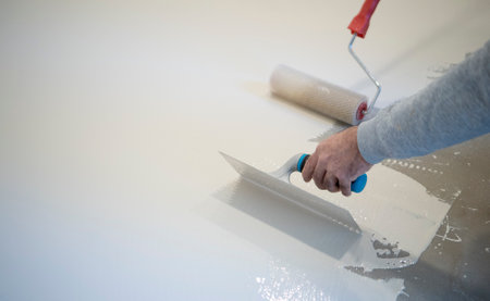 worker painting white polyurethane resin on concrete floor