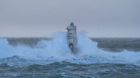 The lighthouse of the Mangiabarche shrouded by the waves of a mistral wind stormの写真素材