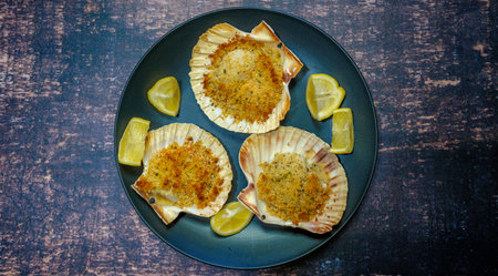 Grilled scallops with garlic and lemon on dark background.