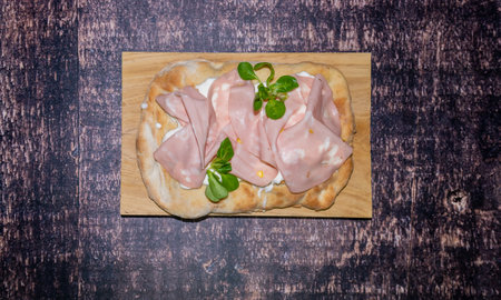 Roman pinsa, variant of the classic Italian pizza topped with mortadella, stracciatella and lamb's lettuce and pistachiosの写真素材