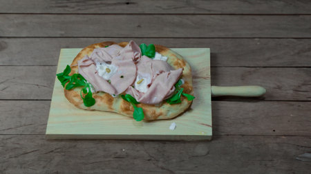 Roman pinsa, variant of the classic Italian pizza topped with mortadella, stracciatella and lamb's lettuce and pistachiosの写真素材
