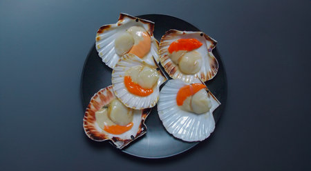 raw scallops ready for cooking on black plate and dark backgroundの写真素材