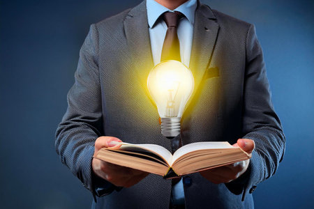 Businessman holding open book with glowing light bulb: new ideas and inspirationの写真素材