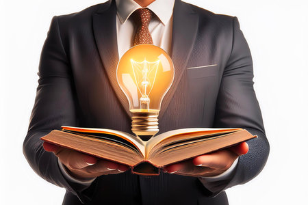 Businessman holding open book with glowing light bulb: new ideas and inspirationの写真素材