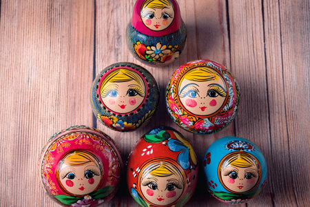 Five colorful matryoshka dolls, also known as Russian nesting dolls, are arranged on a wooden surfaceの写真素材