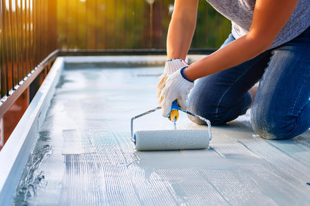 Worker applying blue epoxy on a wooden floor using a brush in a modern apartmentの写真素材