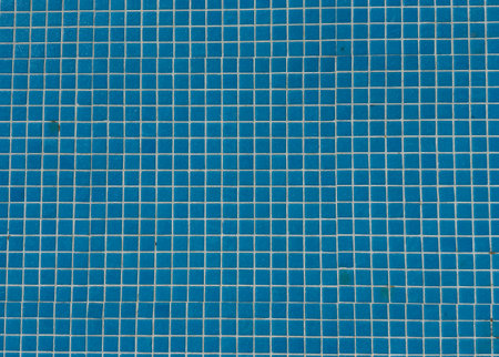 Damaged mosaic tiles falling into empty swimming pool preparations for renovation