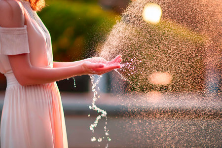 Child catching water in their hand, creating a beautiful splash in bright sunlight