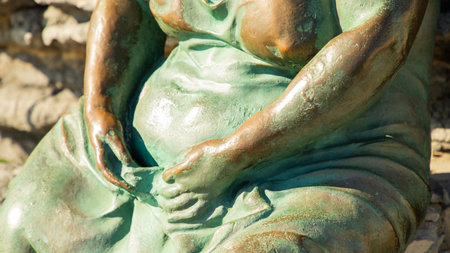 Bronze statue of Mater Naturae, symbol of nature and femininity, set against rocky cliffs in Portovenere.の写真素材