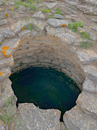 Aerial view of a Nuragic sacred well structure in Sardinia, Italy, surrounded by green grass and ancient stone ruins.の写真素材