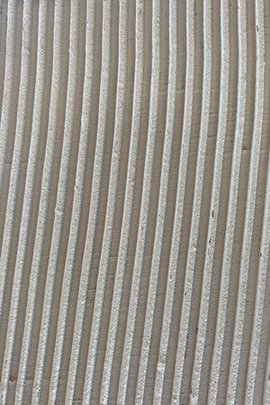 Textured surface with vertical beige lines and soft shadows, abstract architectural backgroundの写真素材