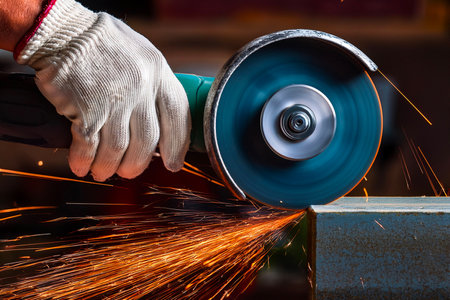 Close-up of worker grinding metal with angle grinder producing intense sparks