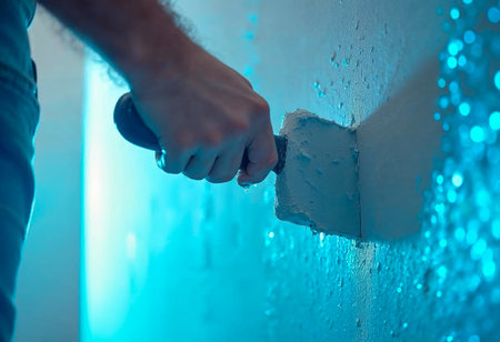 Close-up of plasterer smoothing wall corner using putty knife and white fillerの写真素材