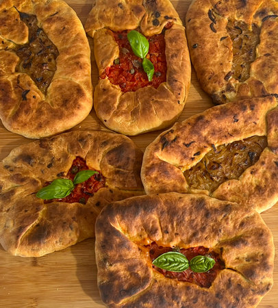Su Mustazzeddu Typical Sardinian flatbread filled with tomato, onion, and fresh basil leavesの写真素材