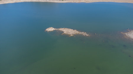 Ancient nuraghe ruins partially submerged in a Sardinian lake, exposed by low waterの写真素材