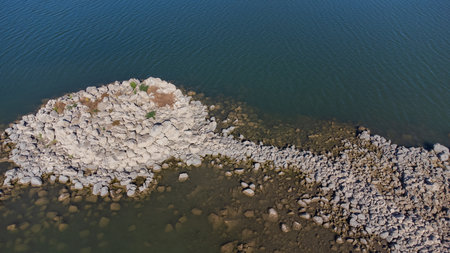 Ancient nuraghe ruins partially submerged in a Sardinian lake, exposed by low waterの写真素材