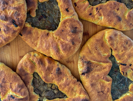Close-up of homemade mustazzeddu flatbreads filled with vegetables, on wooden background